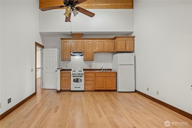 kitchen featuring white appliances, baseboards, a high ceiling, a sink, and light wood-type flooring