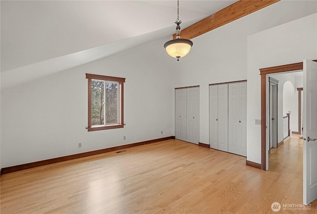 unfurnished bedroom featuring baseboards, multiple closets, visible vents, and light wood finished floors