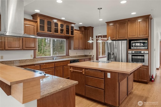 kitchen featuring a sink, appliances with stainless steel finishes, butcher block counters, and wall chimney range hood