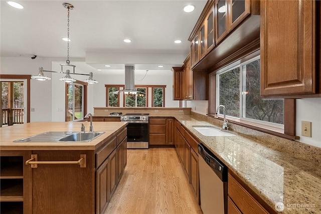 kitchen featuring recessed lighting, island exhaust hood, a sink, stainless steel appliances, and light wood-type flooring