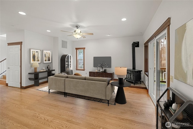 living area with a wood stove, plenty of natural light, and light wood-style flooring