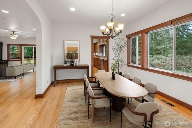 dining space featuring light wood-type flooring, visible vents, recessed lighting, arched walkways, and baseboards