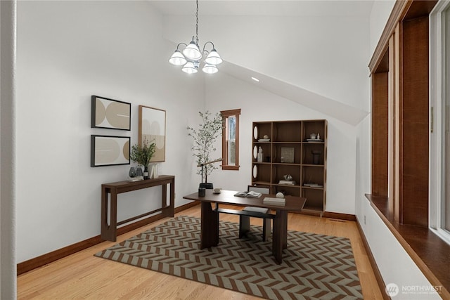 office space with an inviting chandelier, baseboards, light wood finished floors, and high vaulted ceiling