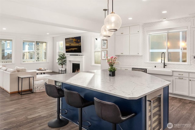 kitchen featuring dark wood finished floors, a center island, open floor plan, and a sink