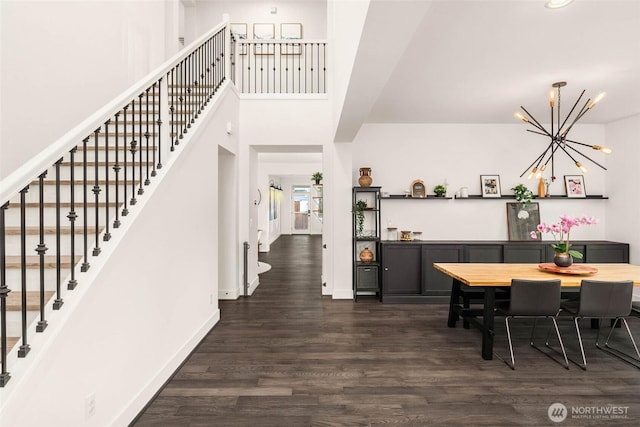 dining space featuring stairway, a chandelier, baseboards, a towering ceiling, and dark wood-style flooring