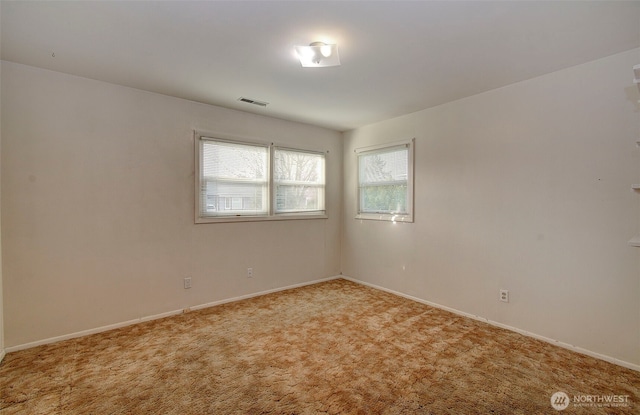 empty room featuring light colored carpet, visible vents, and baseboards