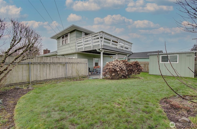 back of property with an outdoor structure, fence, a lawn, and a patio area