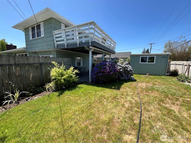 rear view of house featuring a deck, an outbuilding, a yard, and fence