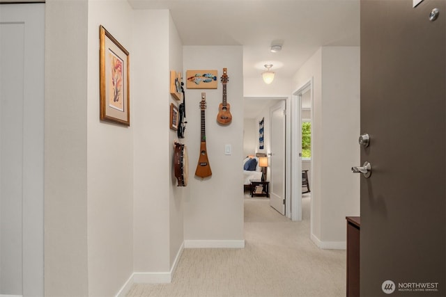 corridor with baseboards and light colored carpet