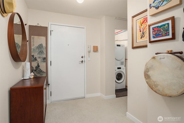 entrance foyer with light carpet, stacked washing maching and dryer, and baseboards