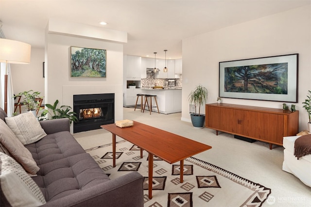 living room featuring light carpet, a fireplace with flush hearth, and recessed lighting