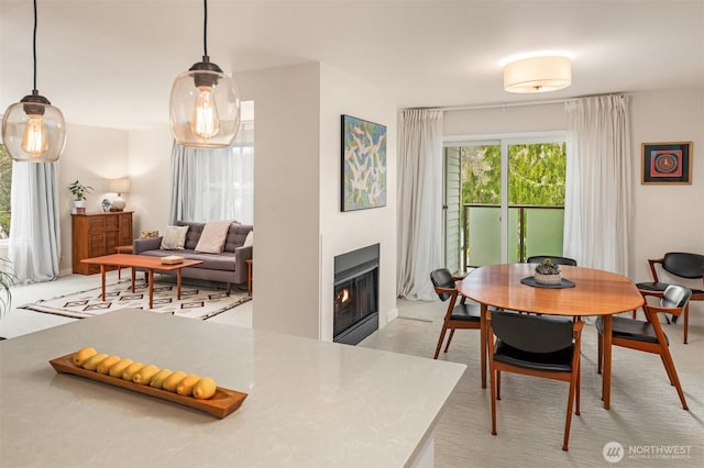 dining area featuring light carpet and a glass covered fireplace