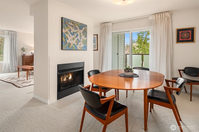 dining room featuring baseboards, light colored carpet, and a fireplace