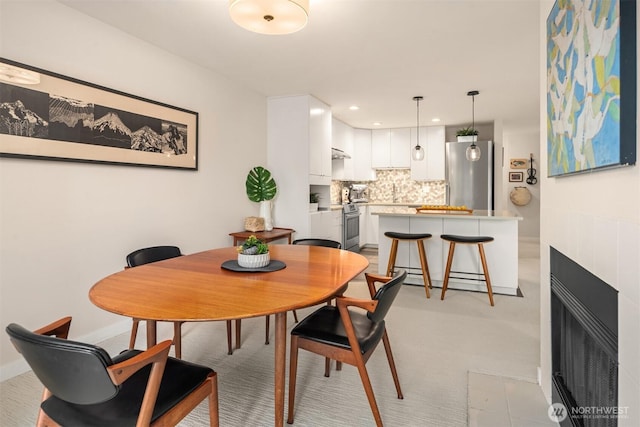 dining area with a tiled fireplace and recessed lighting