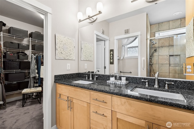 bathroom with double vanity, a shower stall, a spacious closet, and a sink