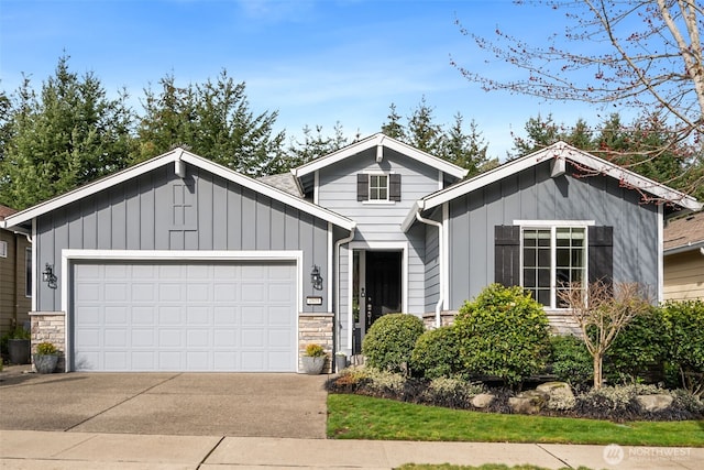 view of front of property with board and batten siding, concrete driveway, an attached garage, and stone siding