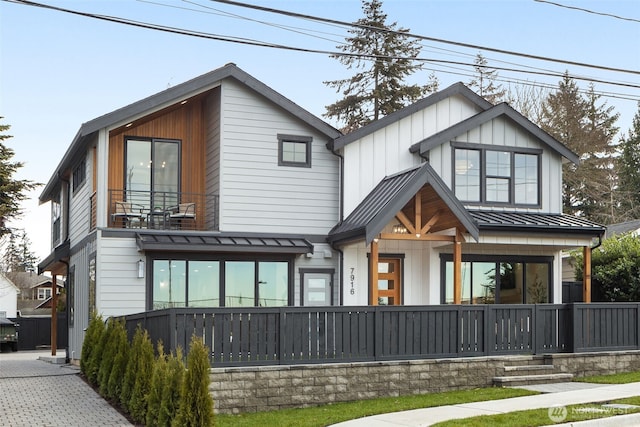 view of front of property featuring a standing seam roof, a porch, board and batten siding, metal roof, and a balcony