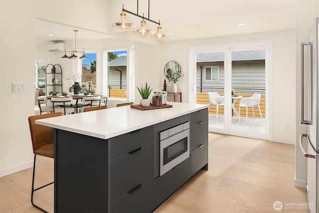 kitchen with light wood finished floors, a kitchen island, an AC wall unit, stainless steel appliances, and modern cabinets