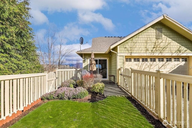 view of yard featuring an attached garage, fence private yard, and driveway