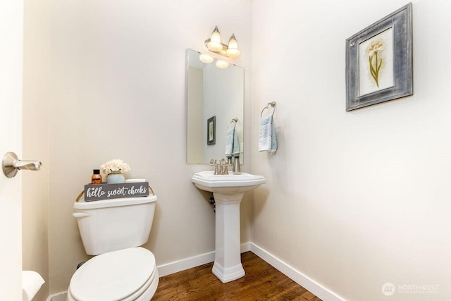 bathroom with a sink, toilet, baseboards, and wood finished floors