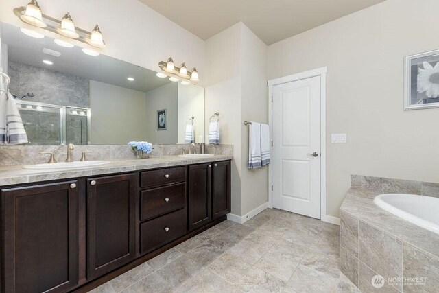 full bathroom with a sink, a garden tub, double vanity, and a shower stall