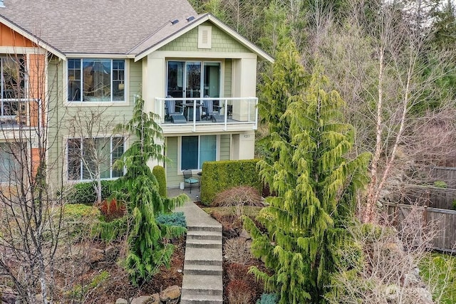 view of front of house with a shingled roof and a balcony