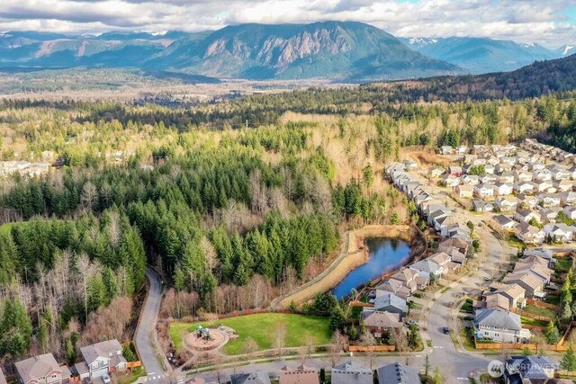 drone / aerial view featuring a view of trees and a water and mountain view