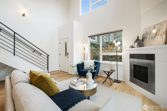 living room featuring baseboards, stairs, a high ceiling, and wood finished floors