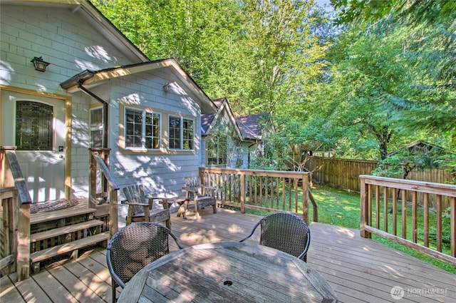 wooden terrace with a yard, outdoor dining space, and fence