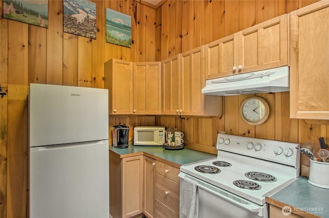 kitchen featuring under cabinet range hood, wooden walls, and white appliances