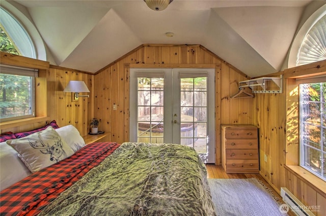 bedroom featuring access to exterior, wooden walls, vaulted ceiling, baseboard heating, and multiple windows