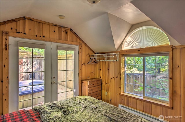 bedroom featuring a baseboard radiator, lofted ceiling, multiple windows, and wood walls