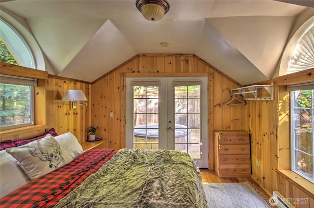 bedroom featuring wood finished floors, a baseboard radiator, lofted ceiling, access to exterior, and wood walls