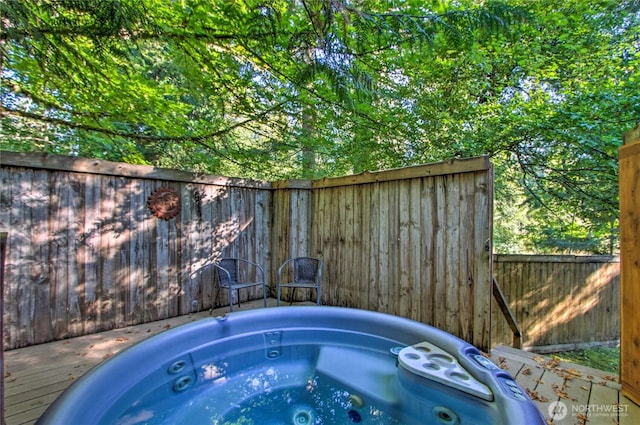 view of pool with hot tub deck surround and fence