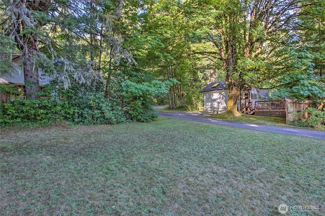 view of yard with an outbuilding, driveway, and a wooden deck