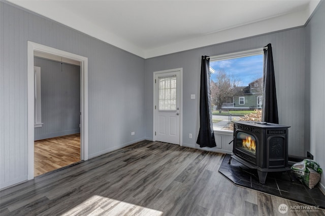 entrance foyer with a wood stove, baseboards, and wood finished floors