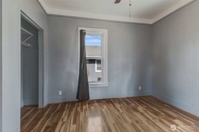 interior space with a ceiling fan, wood finished floors, and baseboards