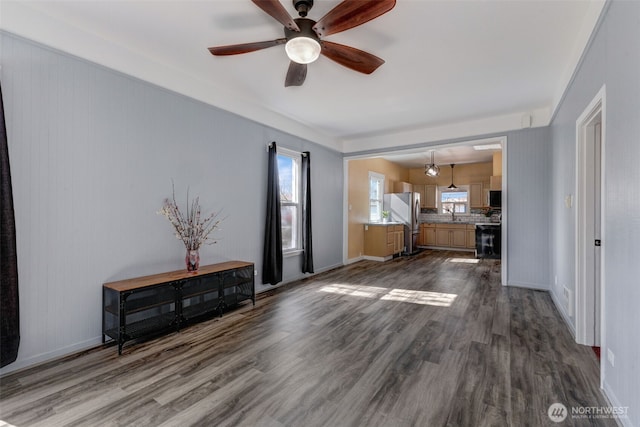 unfurnished living room with baseboards, ceiling fan, and dark wood-style flooring