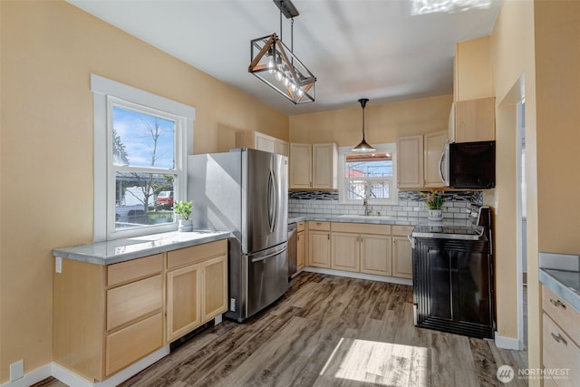 kitchen with light brown cabinetry, a sink, stainless steel appliances, light countertops, and decorative backsplash