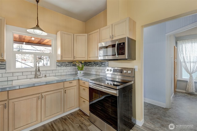 kitchen with a sink, decorative backsplash, hanging light fixtures, light brown cabinetry, and stainless steel appliances