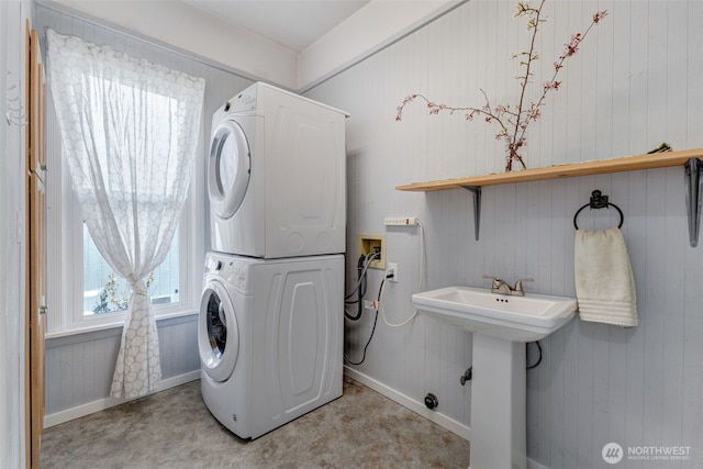 washroom featuring laundry area, stacked washing maching and dryer, and a sink