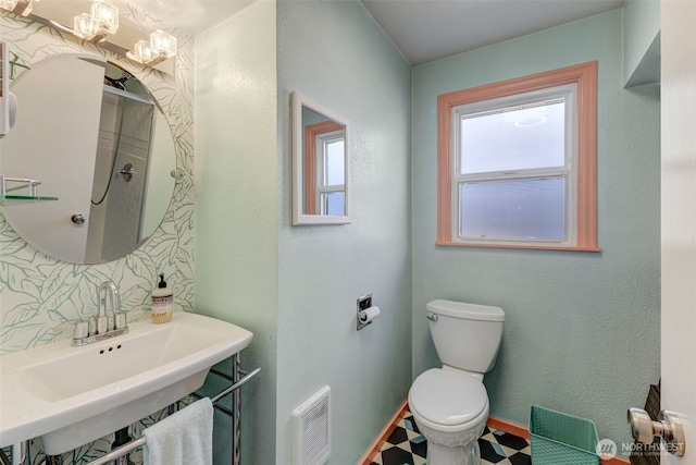 bathroom featuring tile patterned floors, visible vents, toilet, a sink, and baseboards