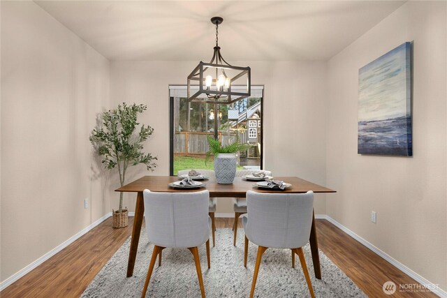 dining space featuring baseboards, an inviting chandelier, and wood finished floors