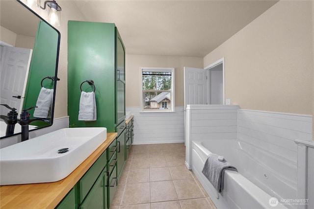 bathroom featuring tile patterned flooring, wainscoting, vanity, and a garden tub