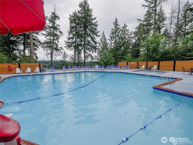 community pool with a patio and fence