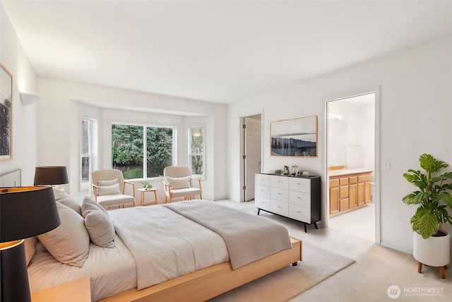 bedroom featuring connected bathroom and light carpet