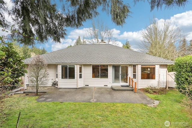 rear view of property featuring a shingled roof, a yard, a patio area, and crawl space