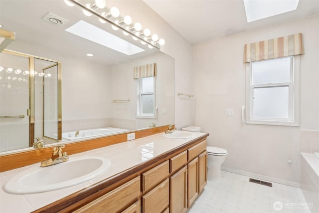 full bathroom with a sink, a garden tub, a skylight, and a shower stall