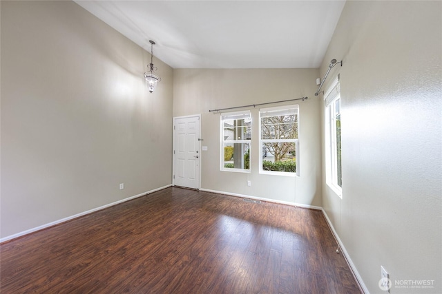 empty room featuring visible vents, high vaulted ceiling, baseboards, and wood finished floors