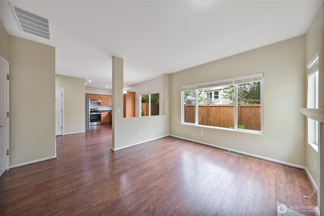 unfurnished living room featuring dark wood-type flooring, baseboards, and visible vents